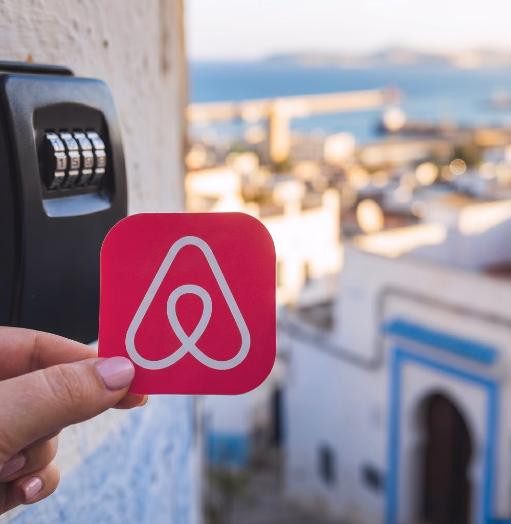 Conciergerie Airbnb au Maroc — boîte à clés sécurisée et logo Airbnb sur fond de ville marocaine